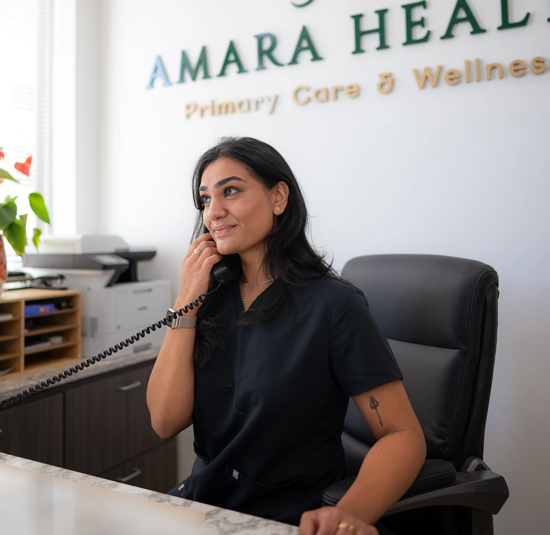 A receptionist answering phone at Amara Health front desk.